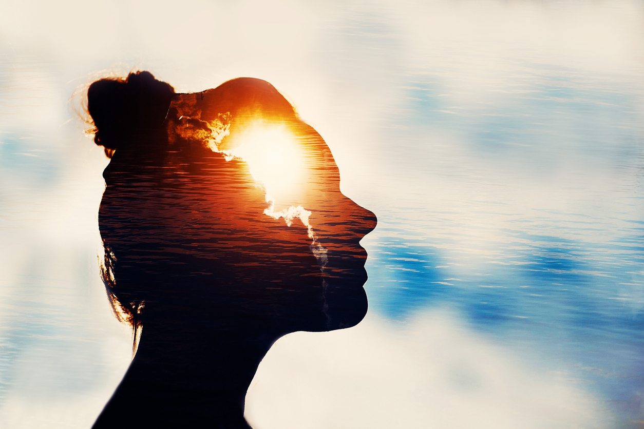 A woman looking at the sky with an overlay of clouds in her head; demonstrates the concept of inspiration